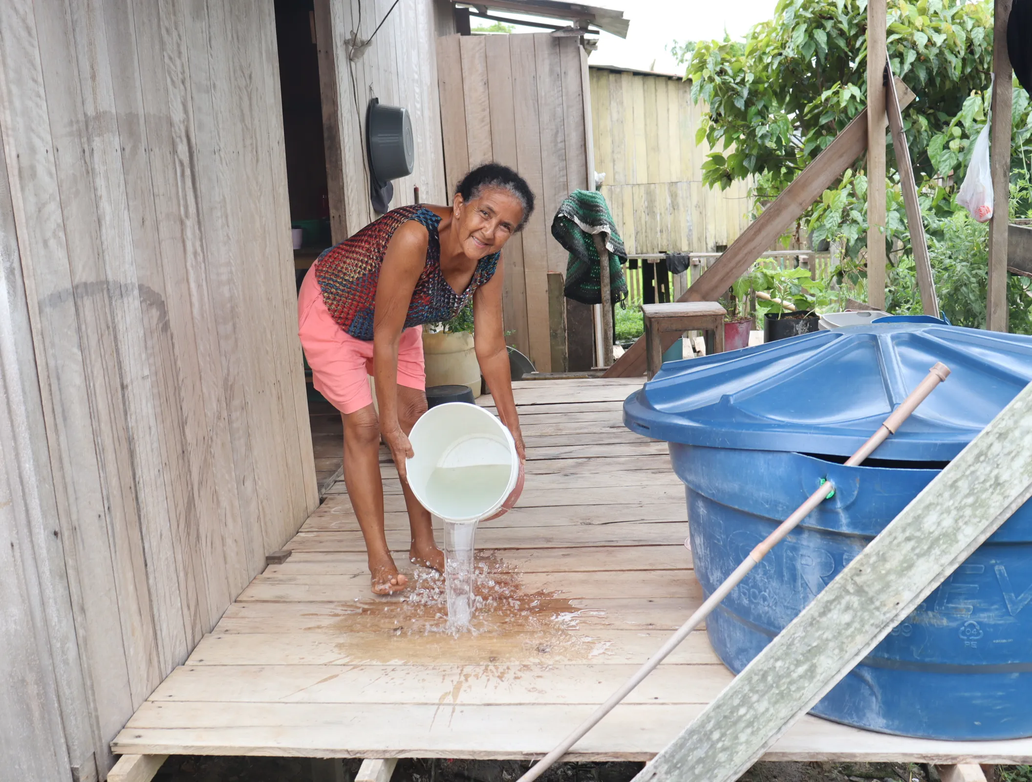 Maria posa com balde na mão ao lado de um tanque na varanda da casa onde mora, no Turrufão. Foto: Elias Nogueira