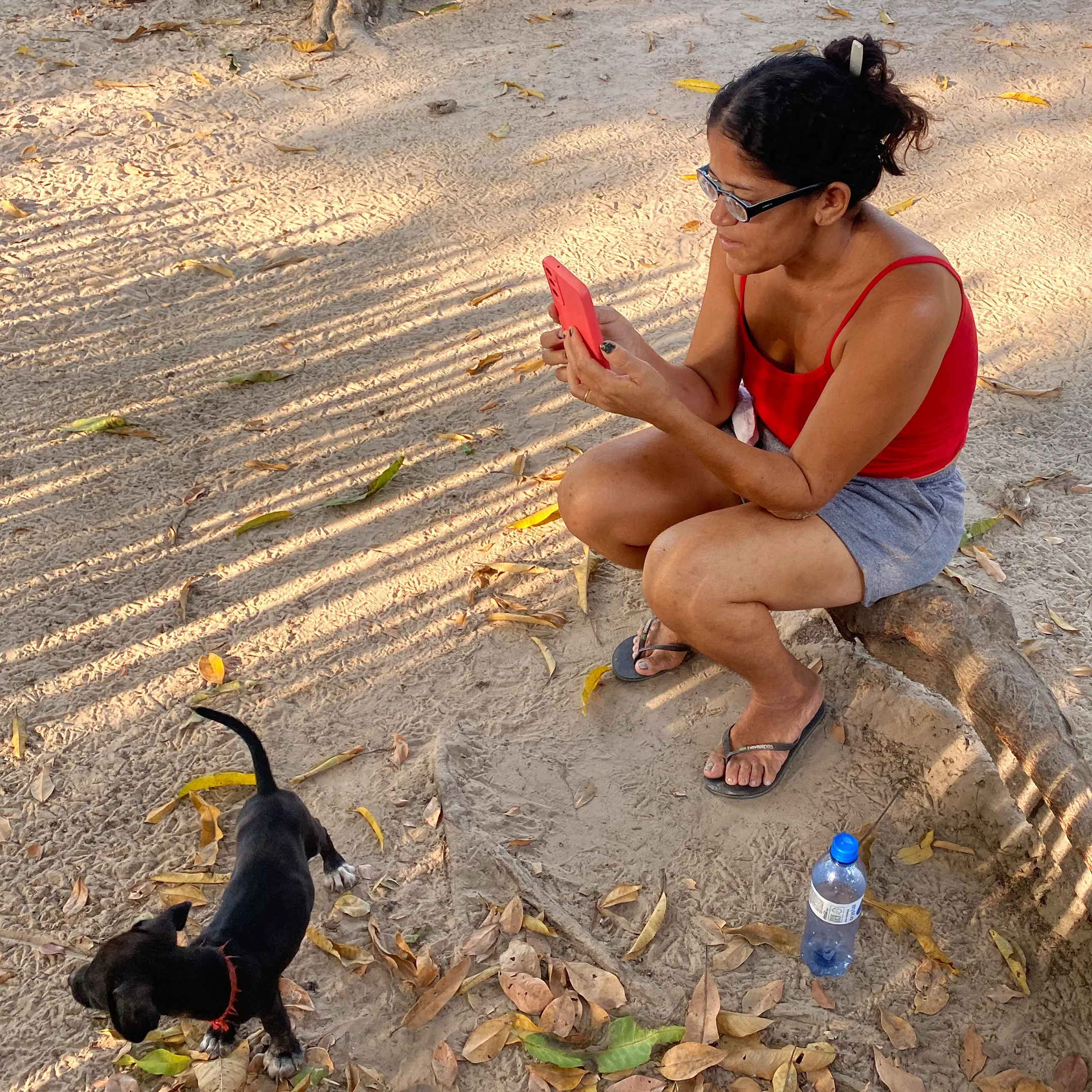 Moradora de Barbado sentava na raiz de uma árvore, acessando o WhatsApp. Foto: Adriana Menezes