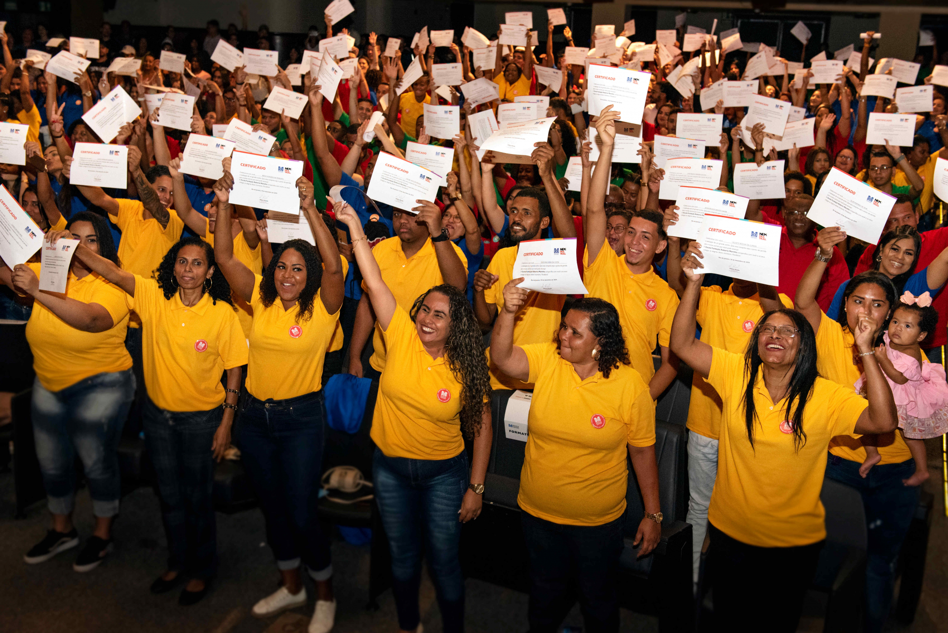alunos da escola da FRM levantando o diploma na cerimônia de formatura