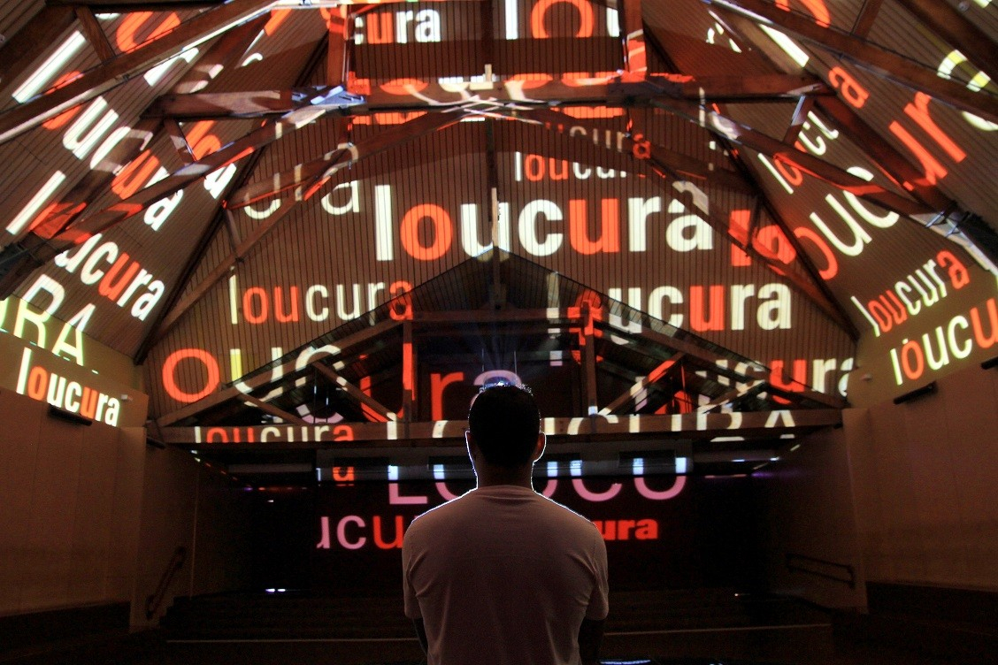 Pessoa de costas olhando para uma projeção com palavras no Museu da Língua Portuguesa