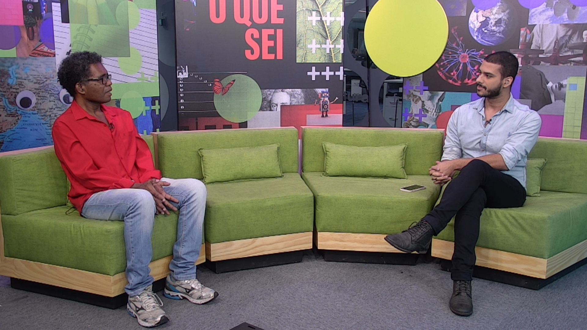 Dois homens conversam sentados no estúdio de gravação do programa Conexão.