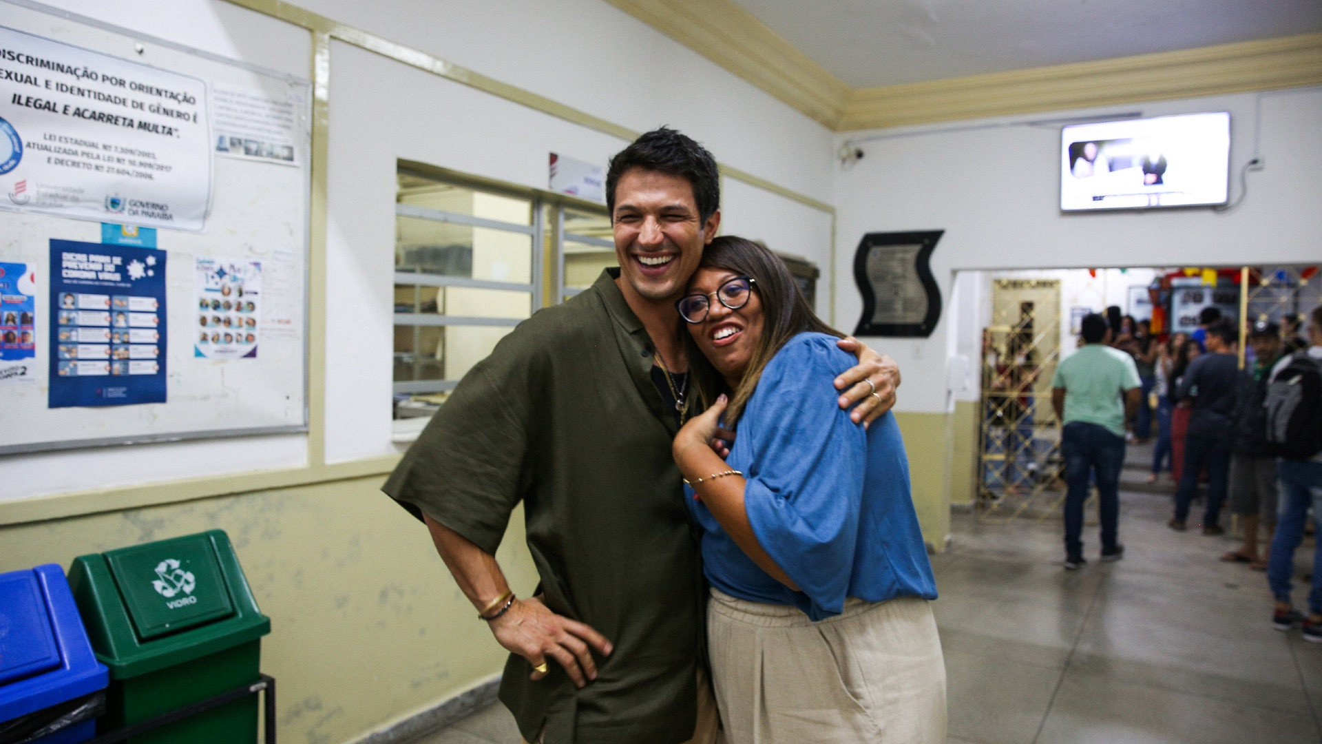 Um homem e uma mulher sorriem, abraçados.
