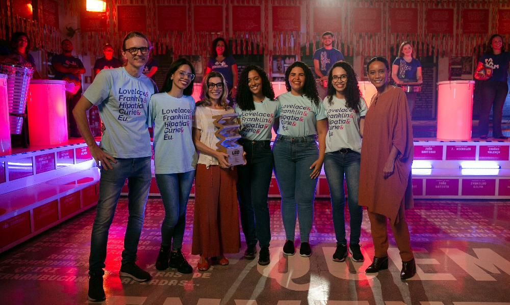 Várias pessoas lado a lado sorriem para serem fotografados.