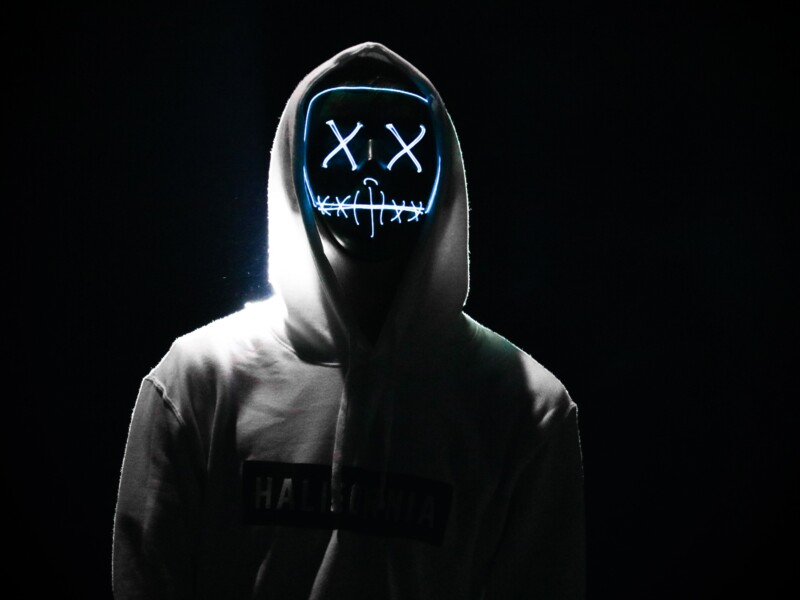 A imagem mostra uma pessoa usando uma máscara com "x" nos olhos