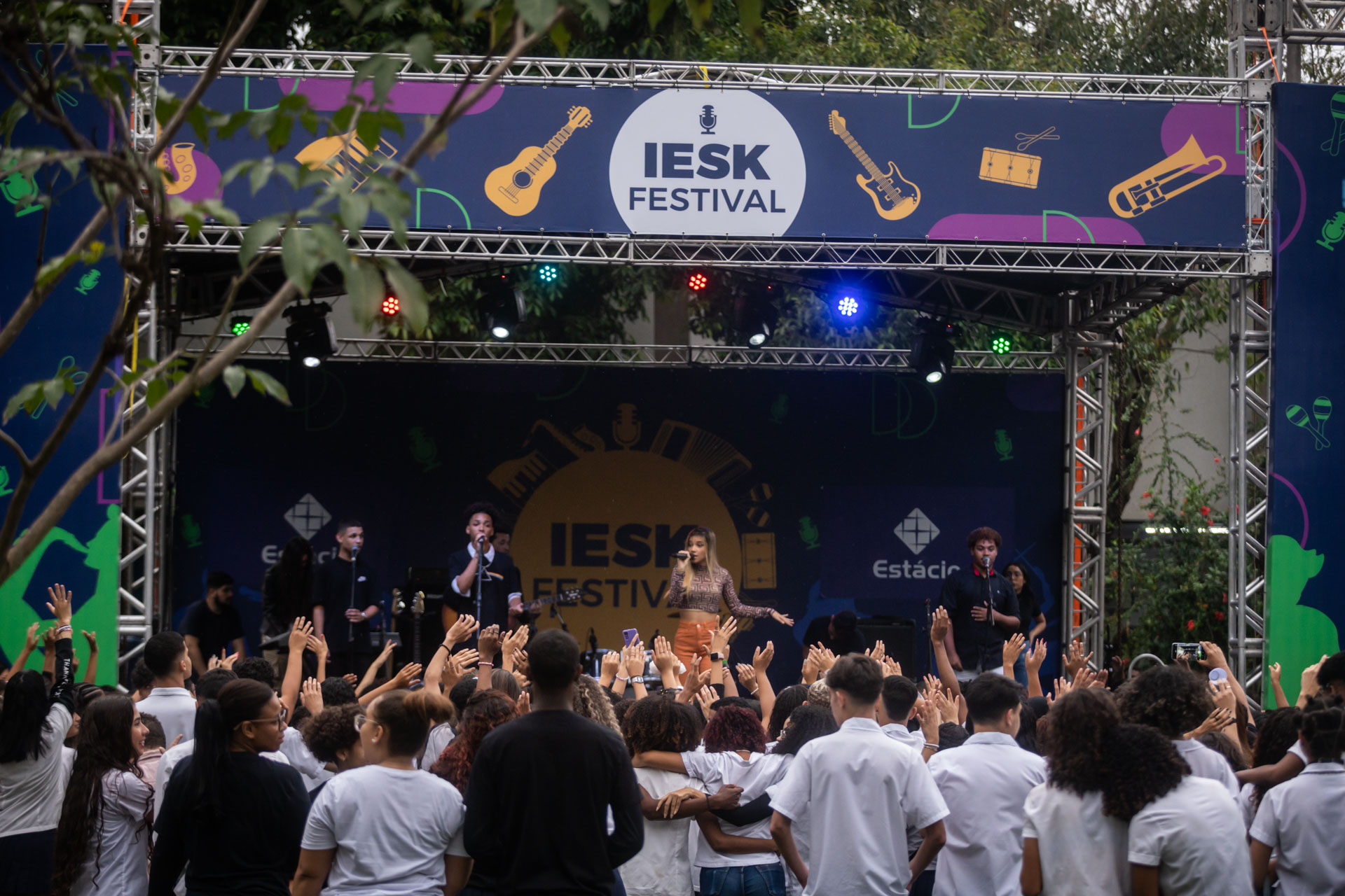 Público estrá diante de um palco com uma banda tocando.