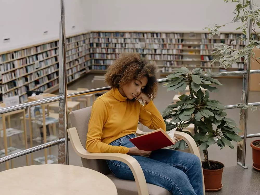 Uma jovem lendo em uma biblioteca