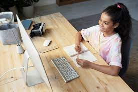 Uma menina sentada mexendo em um computador