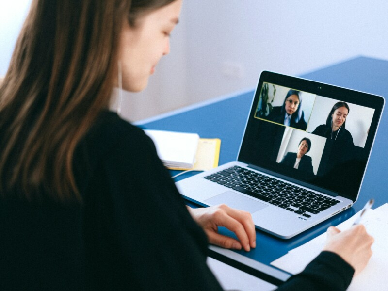 Uma mulger está diante de um laptop em que outras pessoas estão aparecendo.