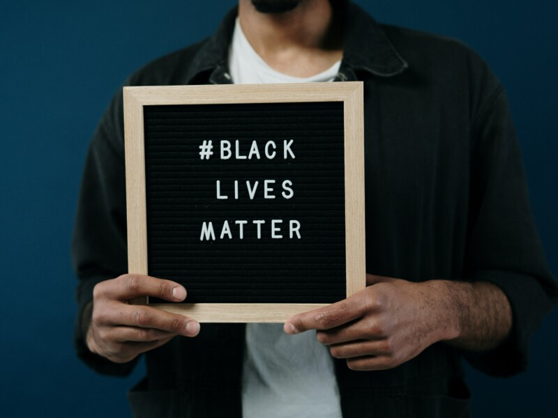 Um homem segurando uma placa escrito Black Lives Matter
