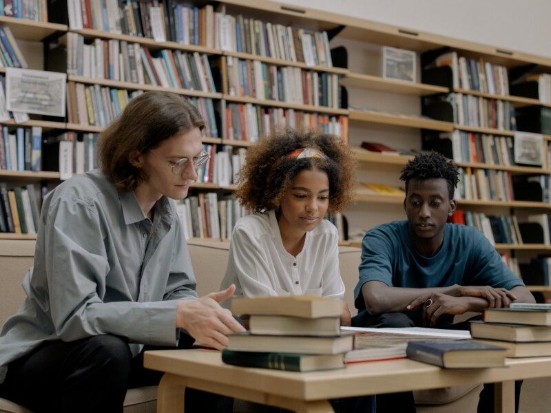 Três estudantes em uma biblioteca