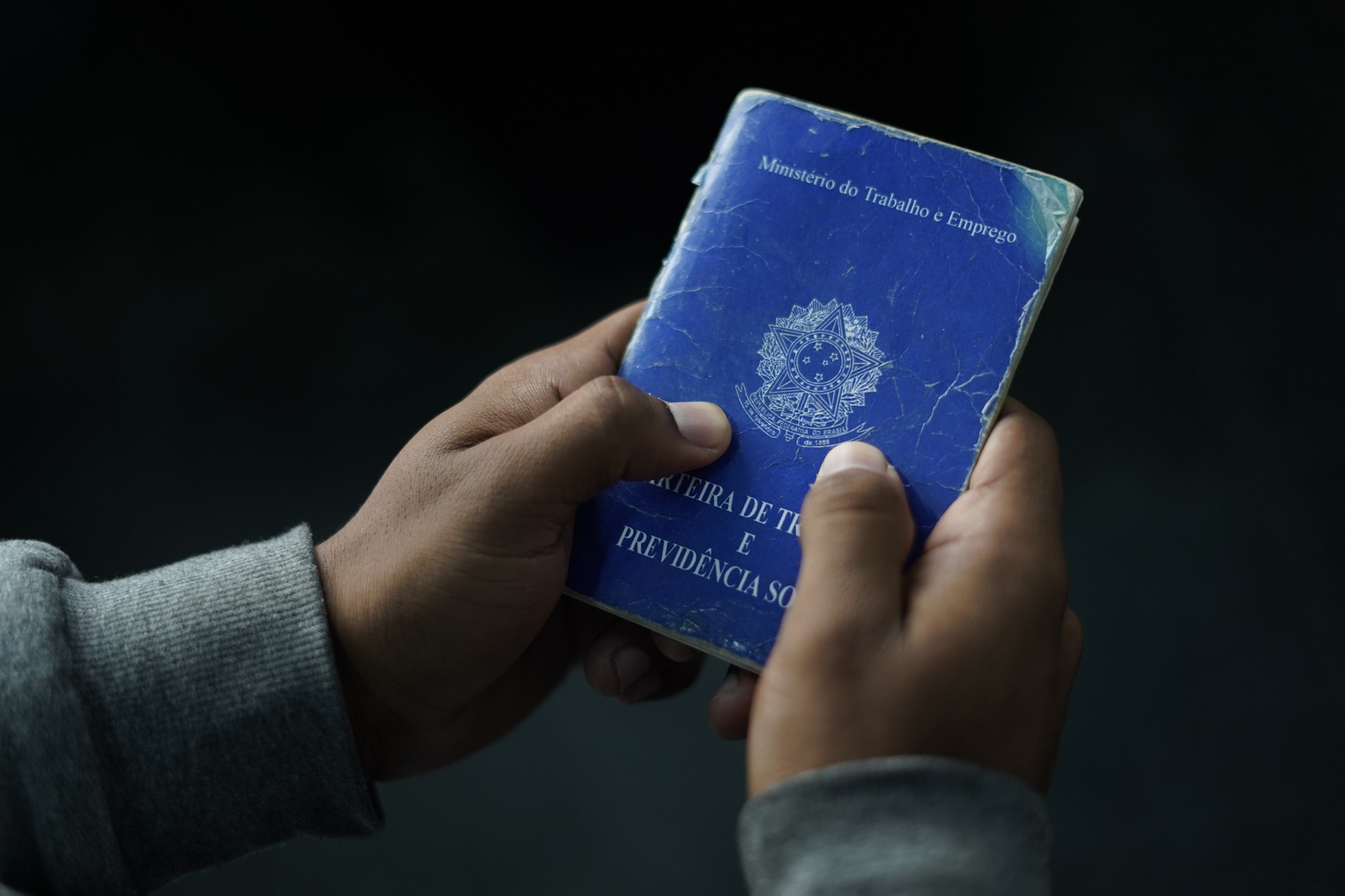 Uma carteira de trabalho sendo segurada pelas mãos de uma pessoa