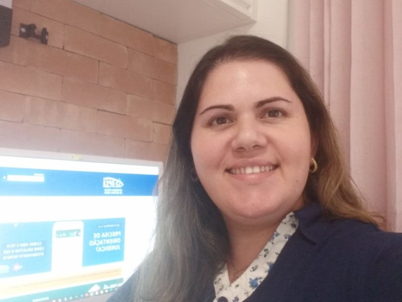 Mulher branca, sorridente e de cabelos compridos olhando para quem bate a foto