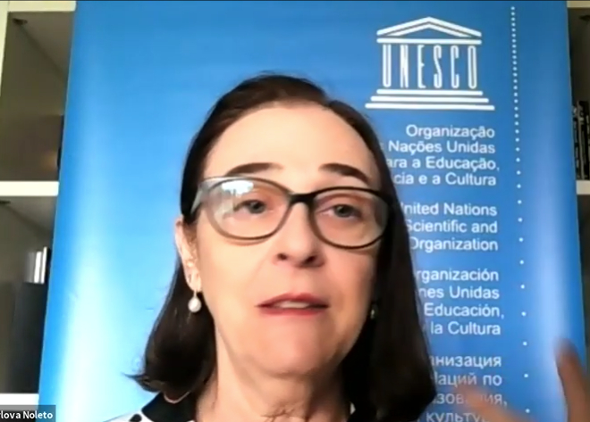 Mulher experiente, branca, de óculos de grau e brincos de pedras