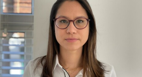 Mulher branca, de óculos de grau, cabelos castanhos soltos e caindo pelos ombros está séria olhando para quem bateu a foto
