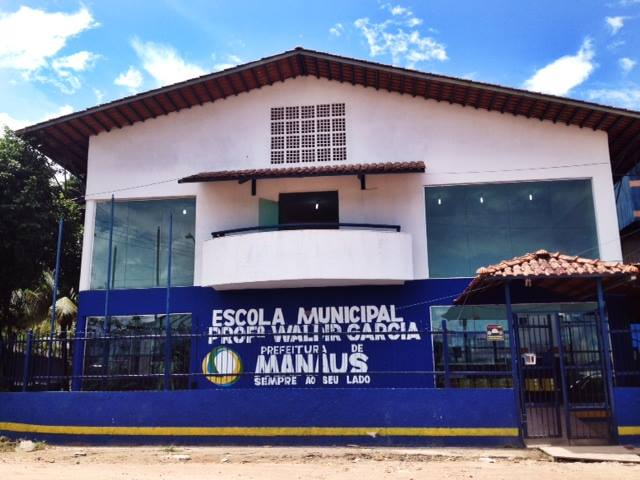 Imagem da fachada de uma escola municipal, nas cores branca e azul