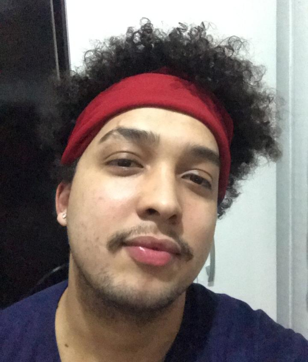 Foto de João Victor, um rapaz que está usando bandana vermelha e de cabelos crespos escuros