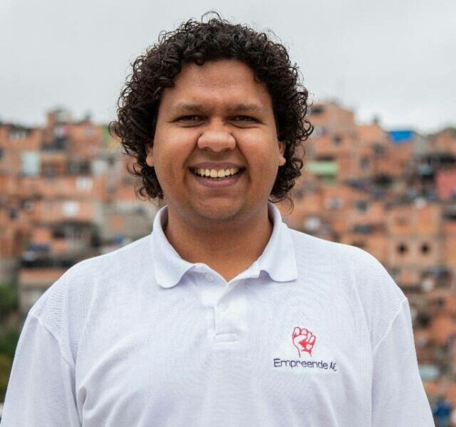 Homem negro de cabelo cacheado e risonho para quem bateu a foto