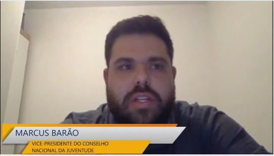 Print da tela de uma videochamada mostrando um homem de barba e bigode e cabelo curto e preto