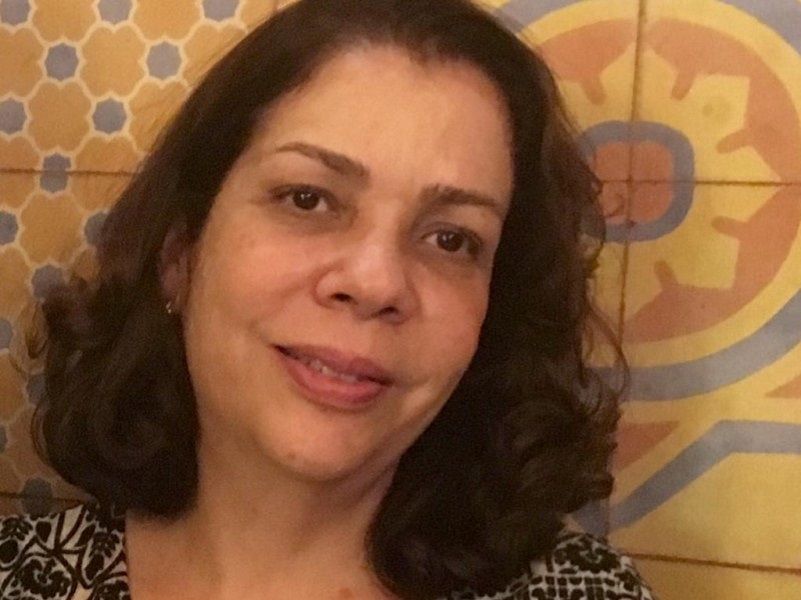 Imagem de uma mulher na casa dos 50 anos, de cabelo solto e castanho escuro