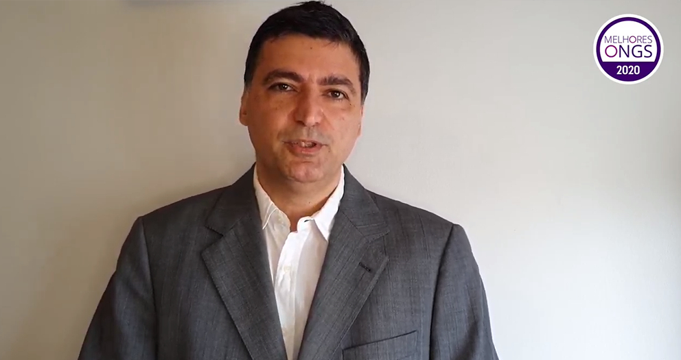 Homem branco com a barba bem feita, cabelo curto escuro e um paletó cinza