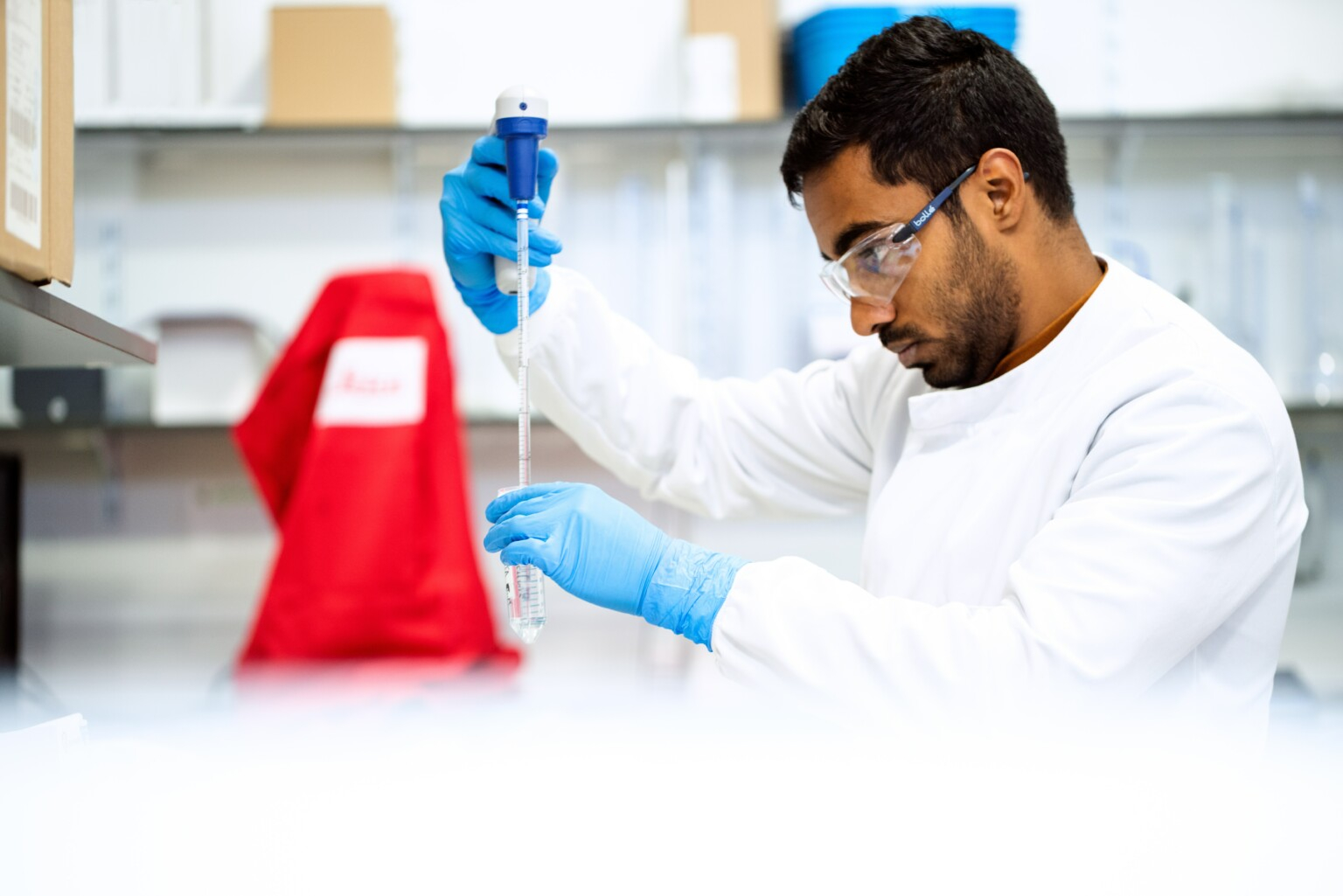 Um cientista moreno em um laboratório mexendo em um frasco e acrescentando algum líquido