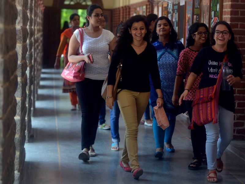 Imagem de várias moças jovens andando bem sorridentes em um corredor