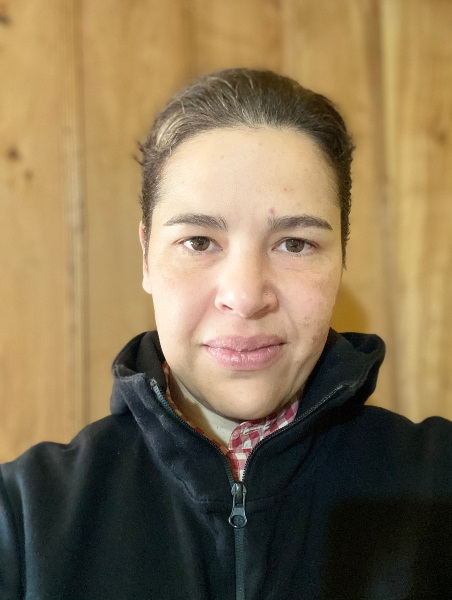 Mulher branca de cabelos claros e presos está olhando séria para a foto. Parece que bateu uma selfie. Está usando casaco escuro de gola rolê