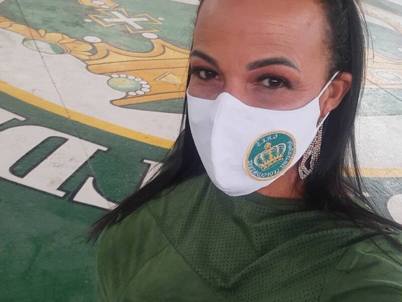 Mulher morena usando máscara de prevenção à covid com a logomarca da escola de samba Imperatriz Leopoldinense