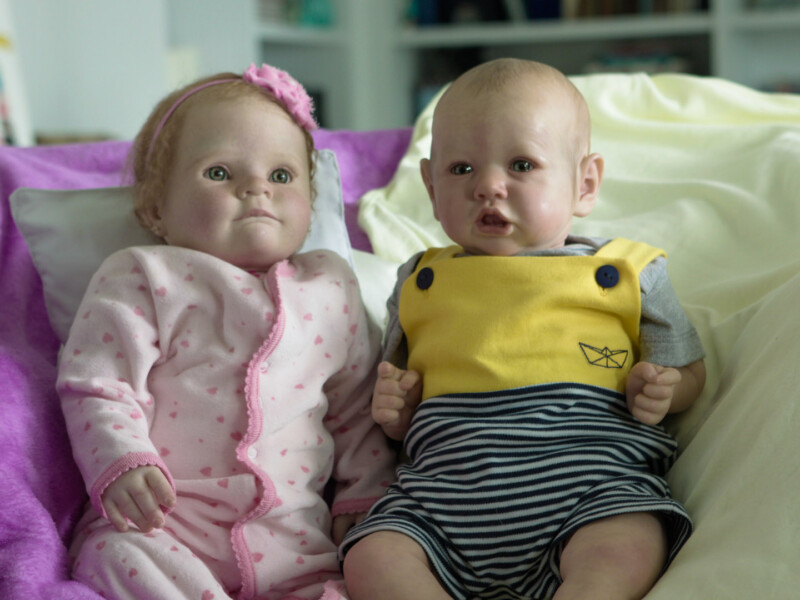 Duas bonecas de bebês...uma de lacinho e roupinha rosa e outra carequinha com um macacão amarelo e preto