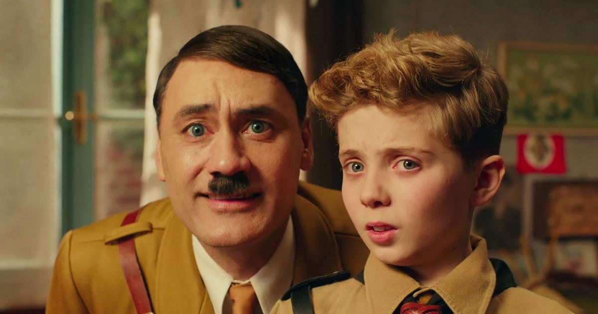 Cena do filme Jojo Rabbit, onde mostra um ator interpretando Adolf Hitler, ao lado de um menino uniformizado