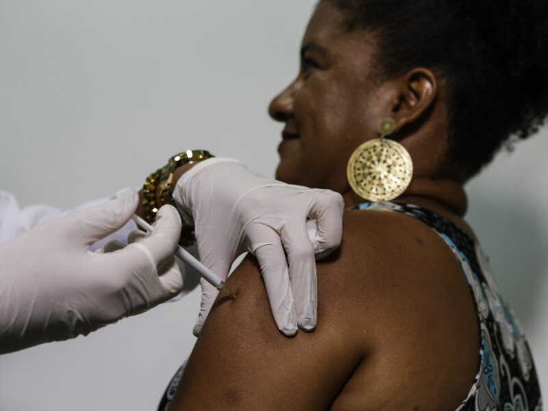 Uma mulher está sendo vacinada tomando uma injeção no braço esquerdo