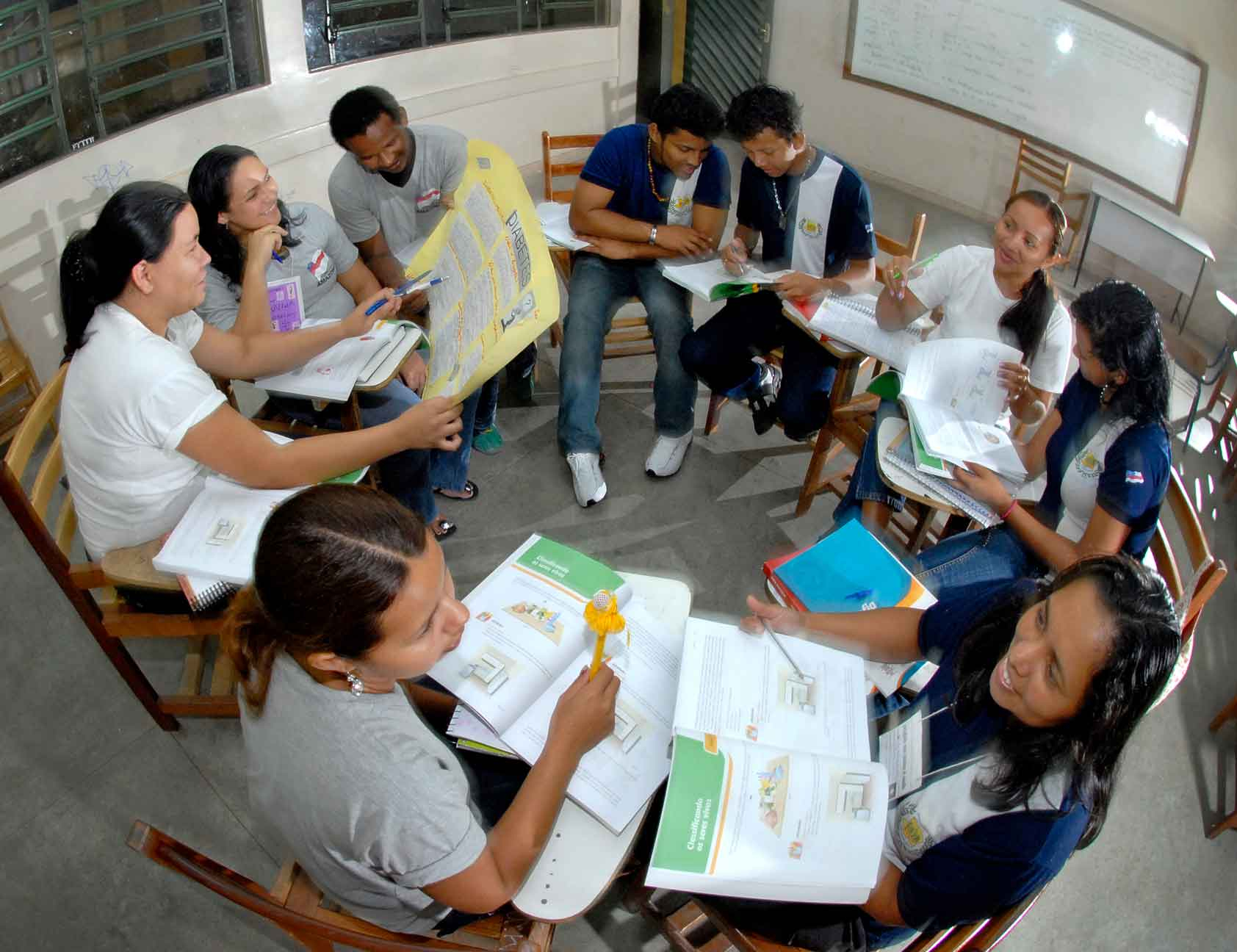 Estudantes do Ensino Médio estão uniformizados e sentados em cadeiras formando um círculo em sala de aula