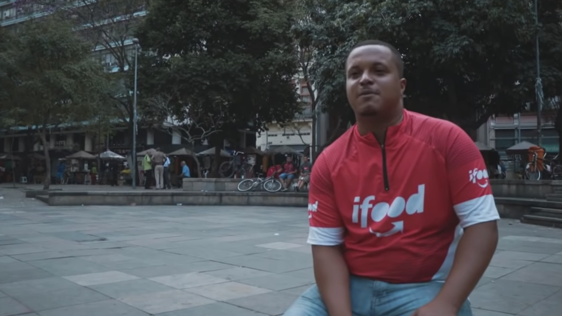 Cena do documentário Vidas Entregues, mostrando um rapaz com camisa do Ifood dando uma entrevista