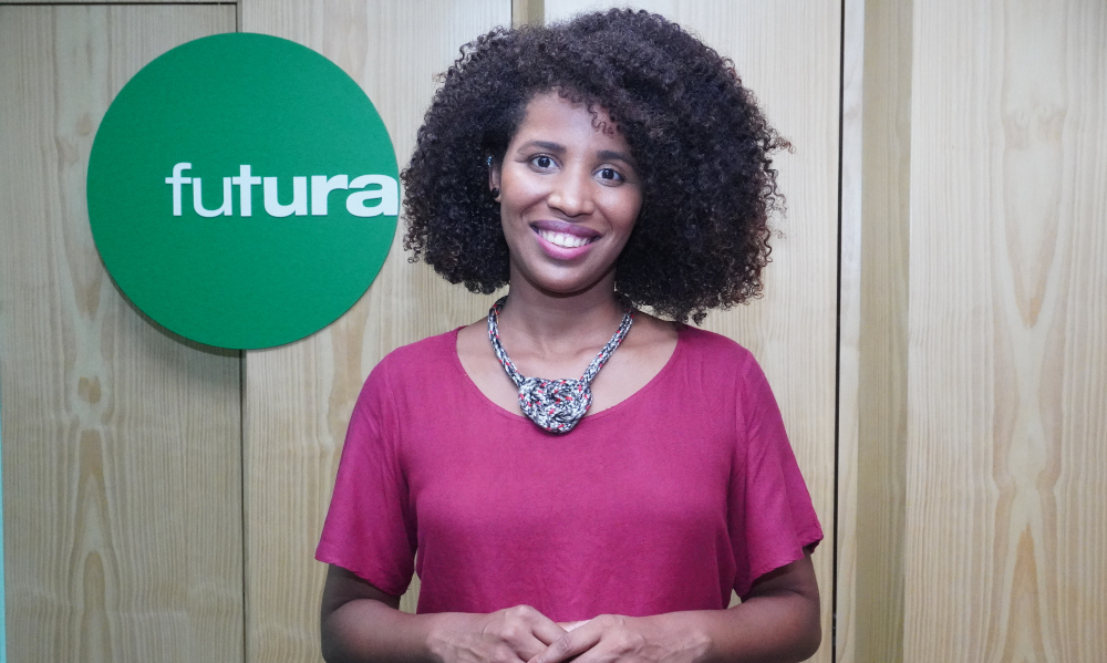 Apresentadora do programa Conexão, Louise Freire, em frente à logomarca do Canal Futura