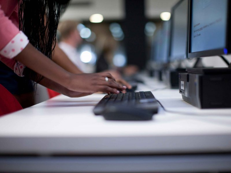 Um teclado de computador está sendo tocado pelas mãos de uma mulher negra
