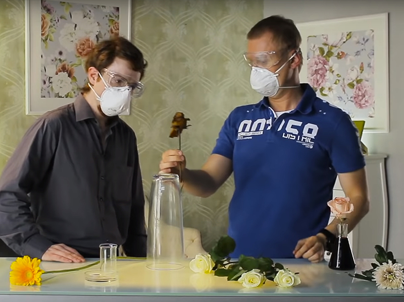 Dois homens de máscara e óculos de proteção estão fazendo algum tipo de experimento