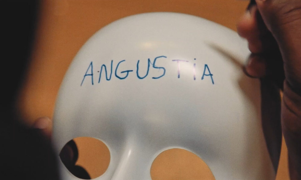 Máscara branca típica de teatros antigos está com a palavra "angústia" escrita em azul na testa
