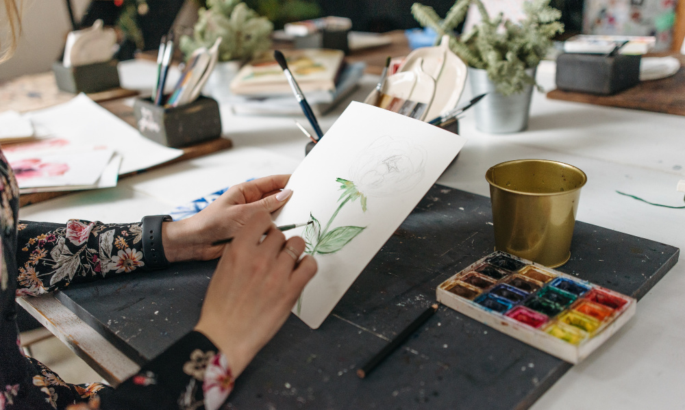 Uma pessoa pintando uma flor em uma tela pequena