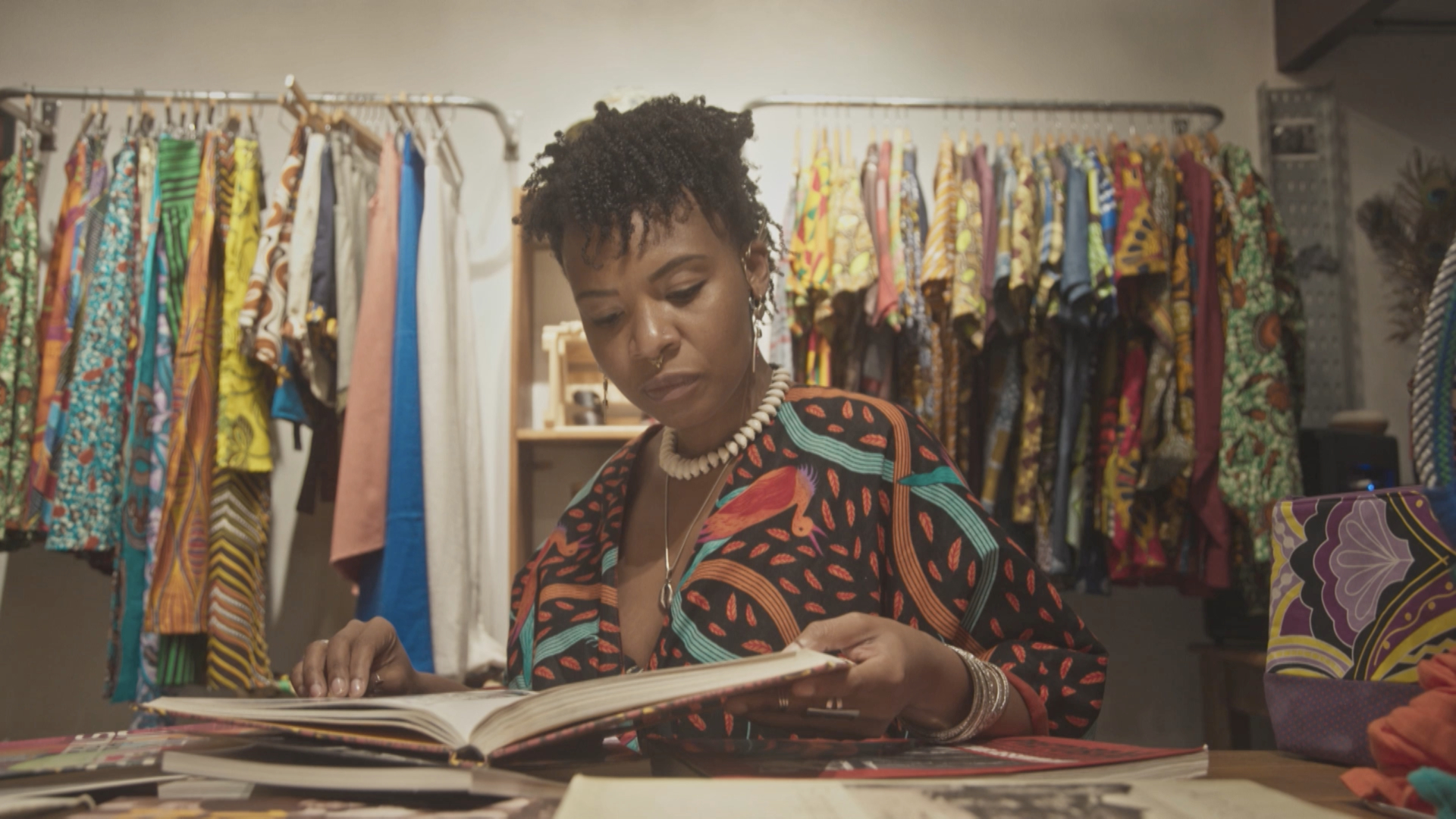 A imagem mostra uma estilista negra em um ateliê