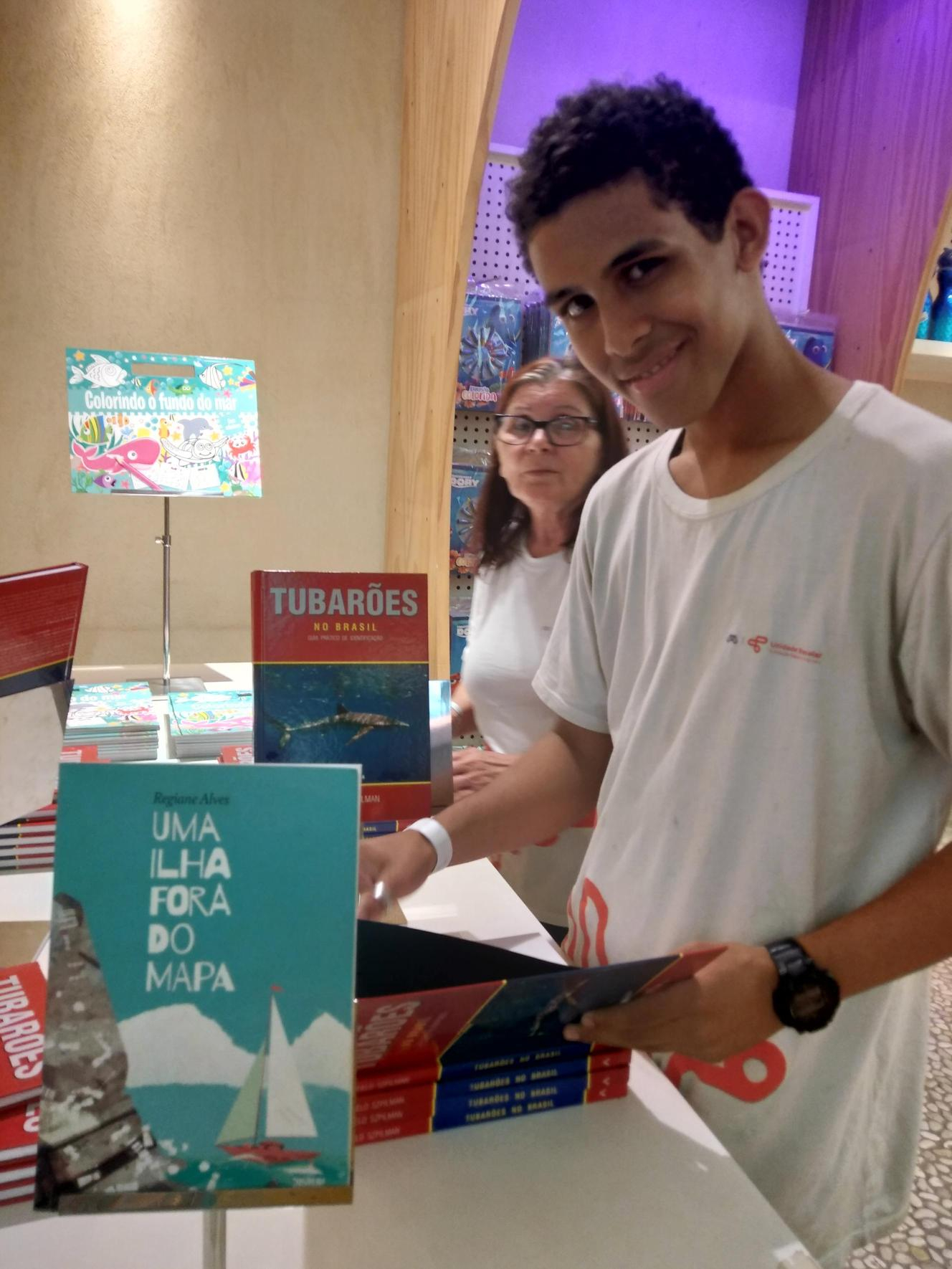 Um jovem sorri enquanto abre um livro.