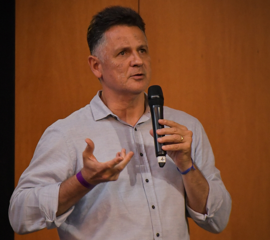 Um homem branco, de cabeço preto, fala ao microfone.
