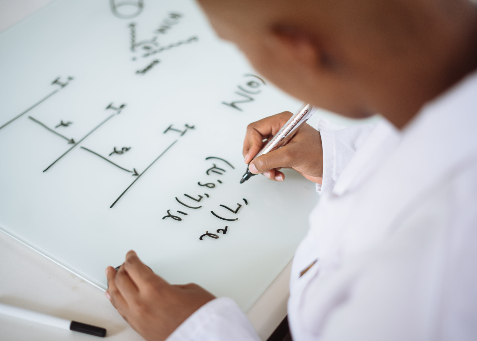 Um menino fazendo exercícios matemáticos em uma superfície branca