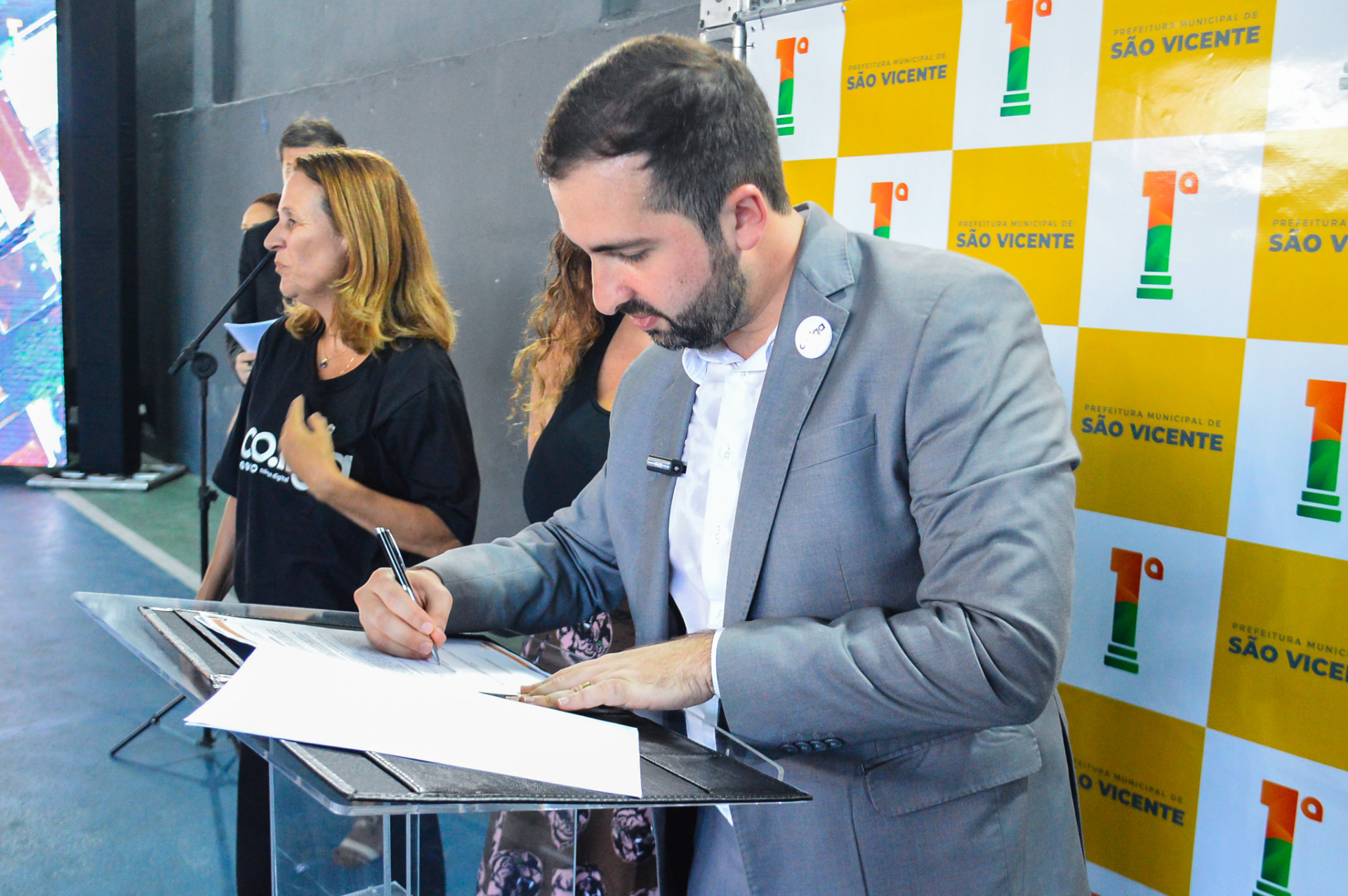 Um homem de terno assina um papel que está sobre um púlpito.