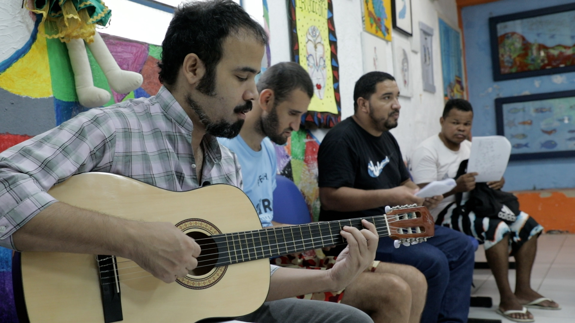 A imagem mostra um grupo de homens tocando violão