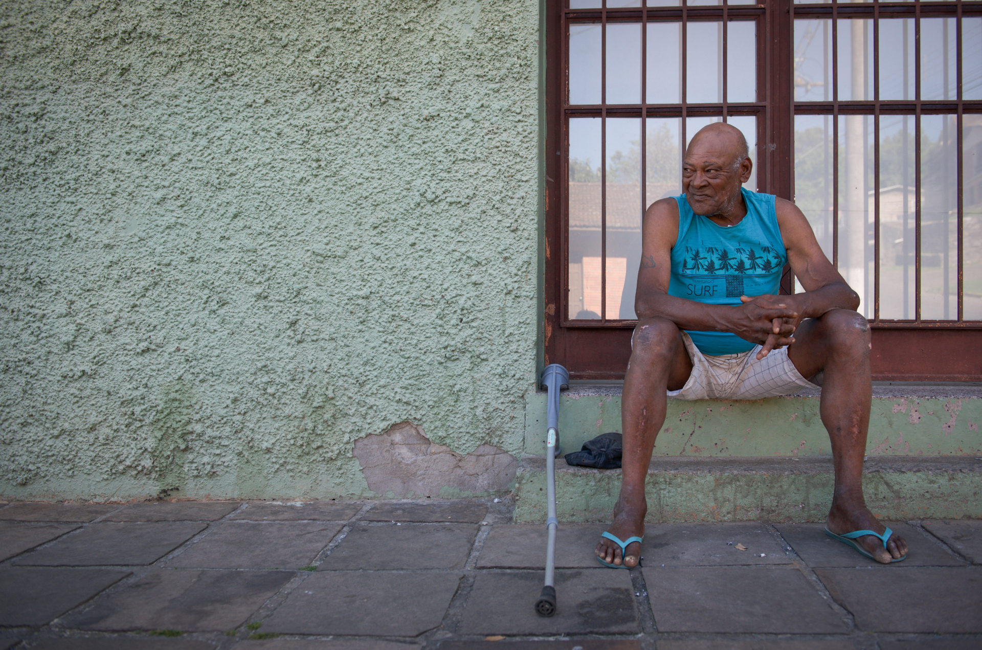 Um senhor negro está sentado, olhando para o lado. 