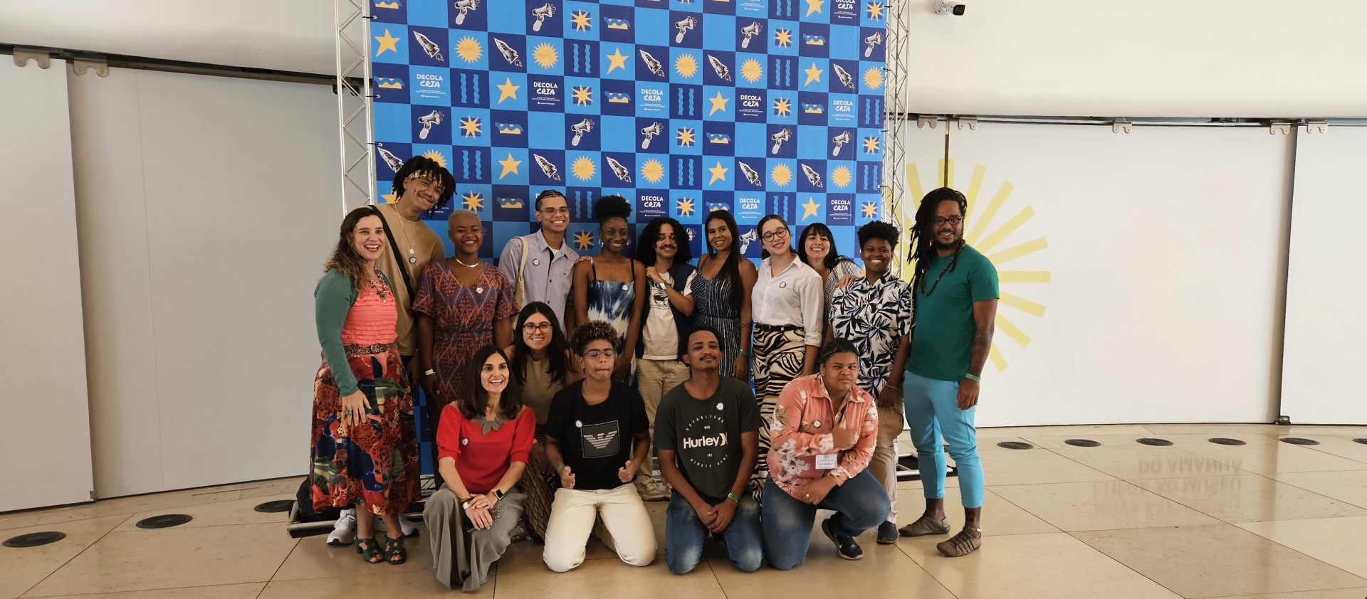 Jovens de pé e agachados (duas fileiras) sorriem para a foto.