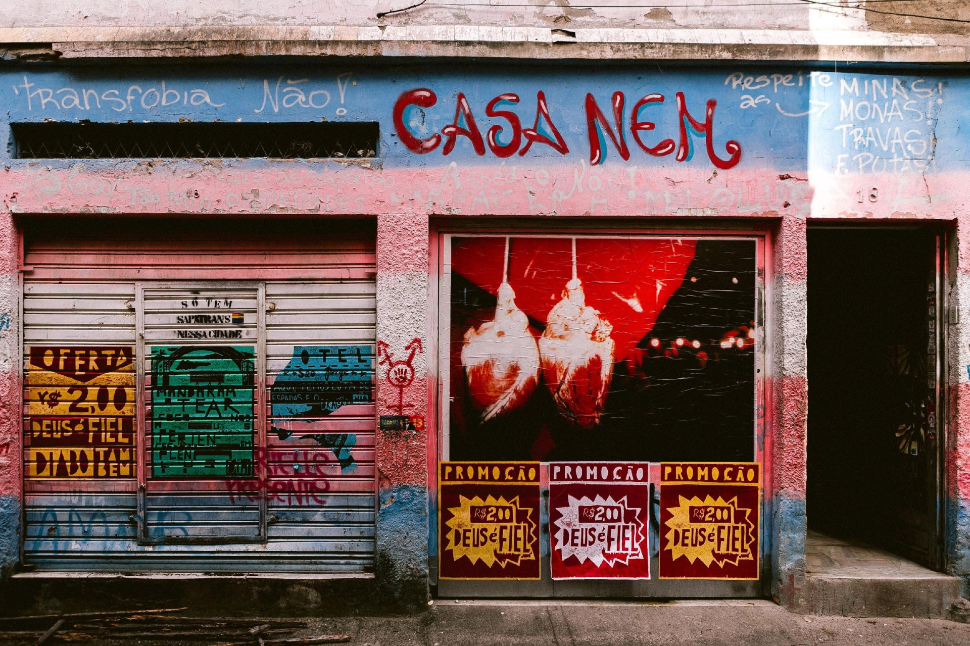 Foto de uma parede externa de um mercado, com cartazes com anúncios de produtos e seus preços.