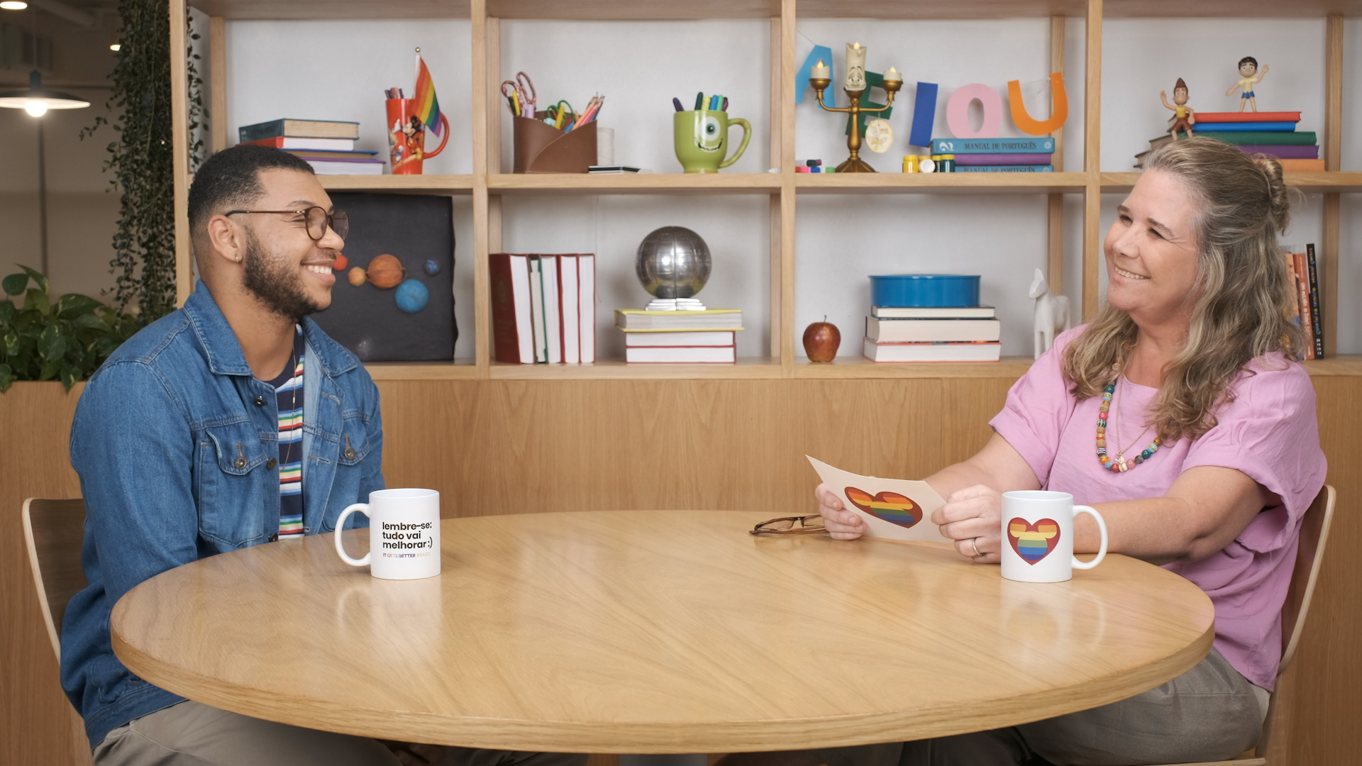 Um homem e uma mulher sorriem, sentados à mesa.