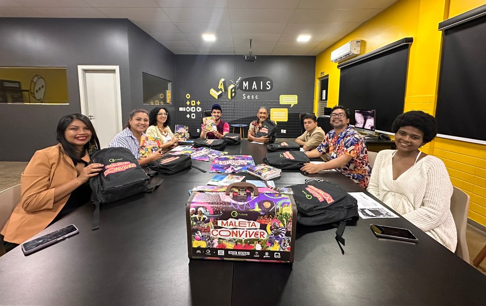 Um grupo de pessoas sentadas e reunidas em volta de uma mesa