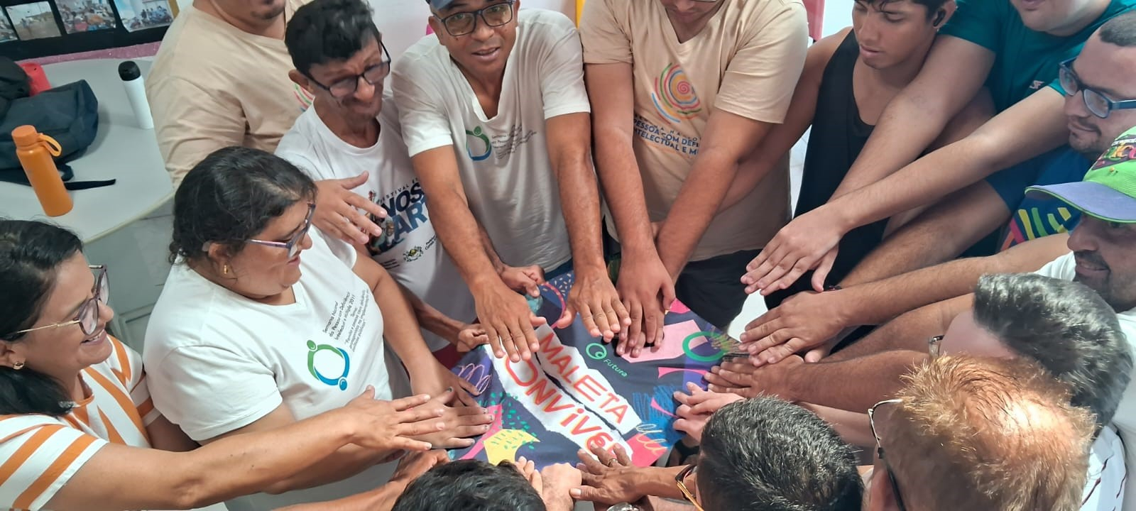 Um grupo de pessoas organizadas em roda e com as mãos estendidas